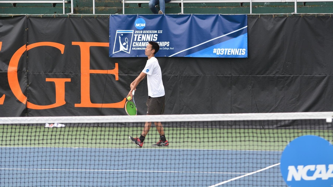 Daniel Park prepares to serve at the NCAA Championships with an NCAA banner on the fence behind him